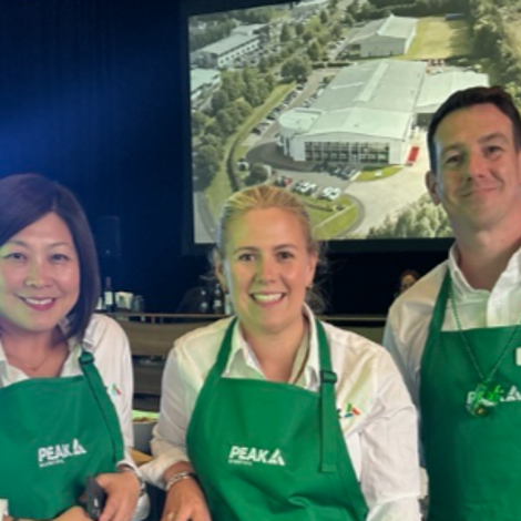 Two women and a man in green PEAK Scientific aprons